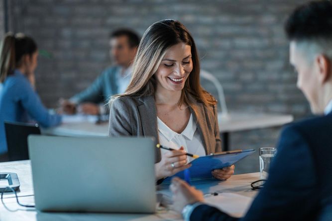 young-happy-businesswoman-reading-reports-while-going-through-paperwork-working-with-colleague-office